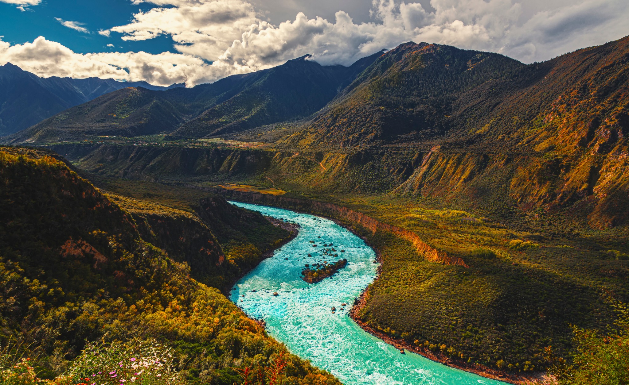 A turquoise river carving a path through a broad mountain valley